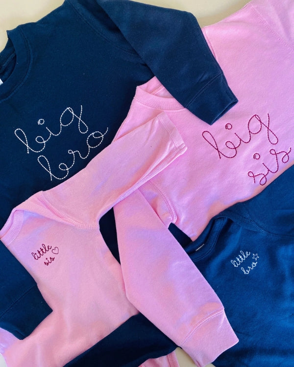 Pink crewneck sweatshirt embroidered with “big sis” in maroon script